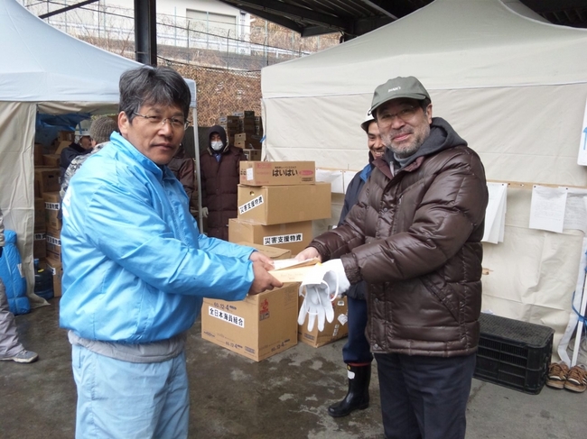 雄勝町災害対策本部に髙橋中央執行委員が、北海道民からの温かいメッセージを手渡す様子。